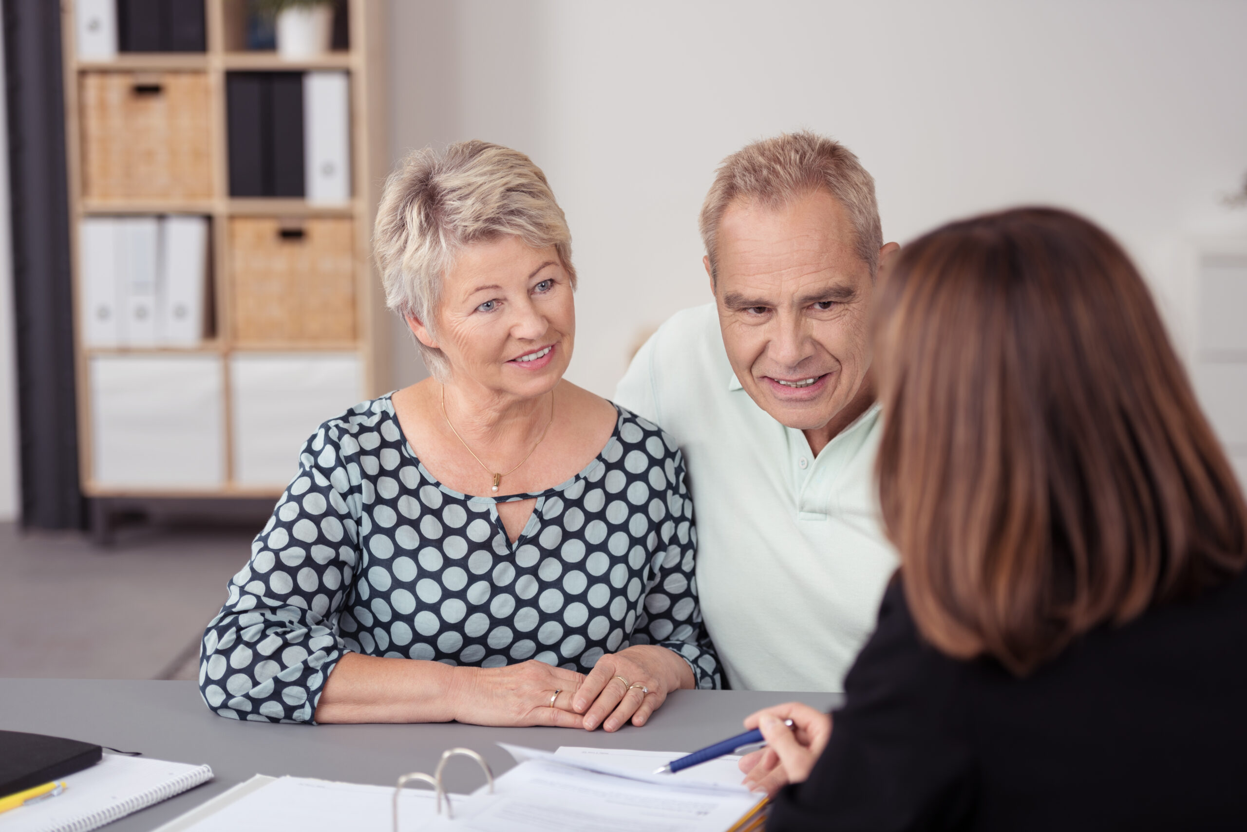 Senior Couple Listening to Female Agent Discussing middle aged couple listening to business woman at desk