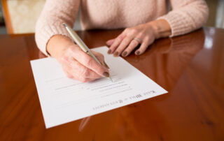 senior woman sitting at a table her writing a will