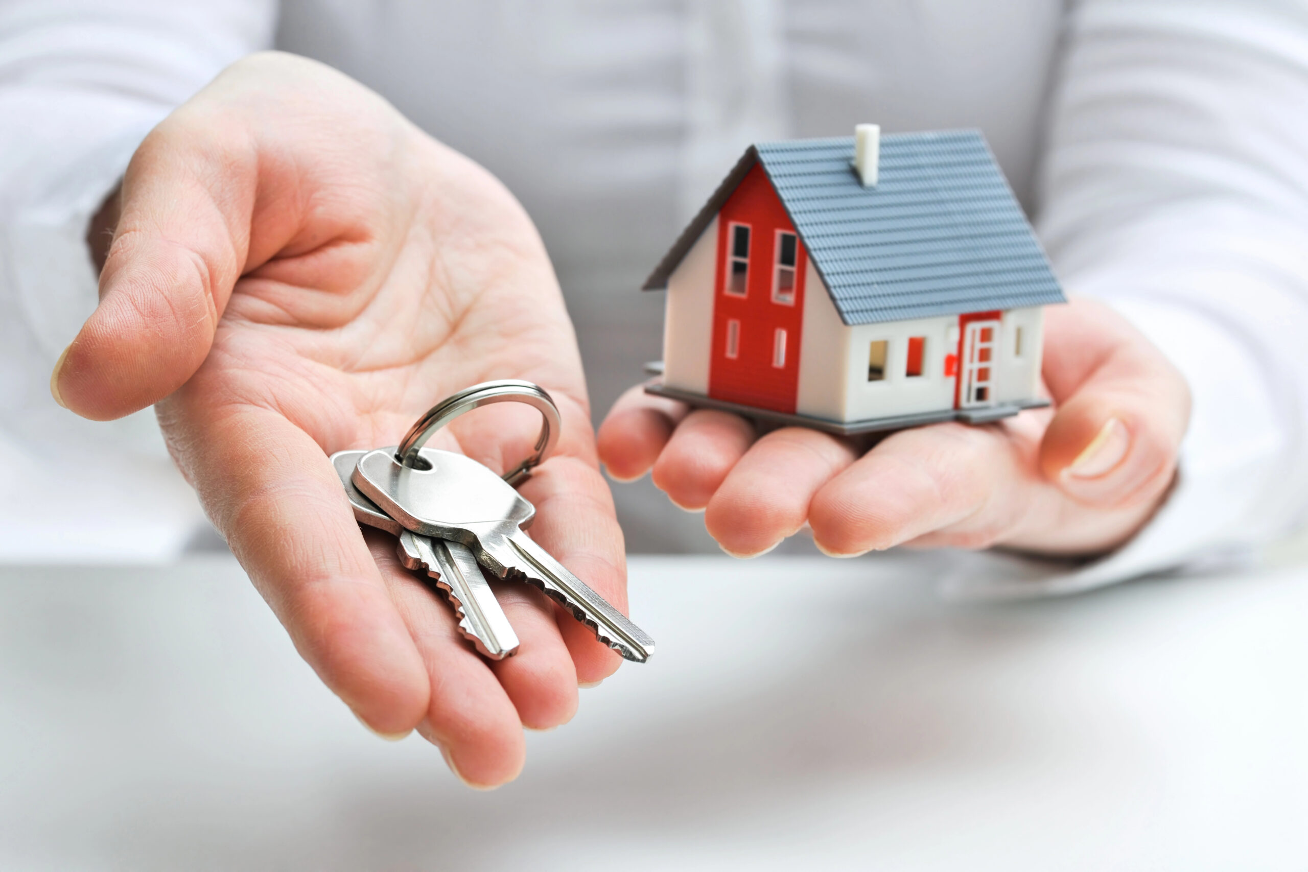 Depositphotos_21515189_XL man holding miniature house in left hand and a set of keys in his right hand